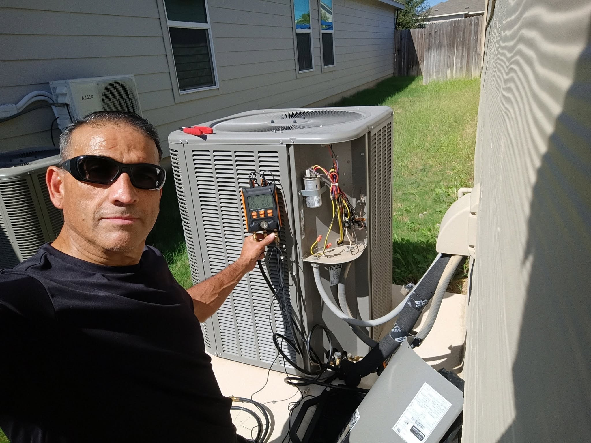 Manny checking refrigerant pressures on an outdoor AC unit