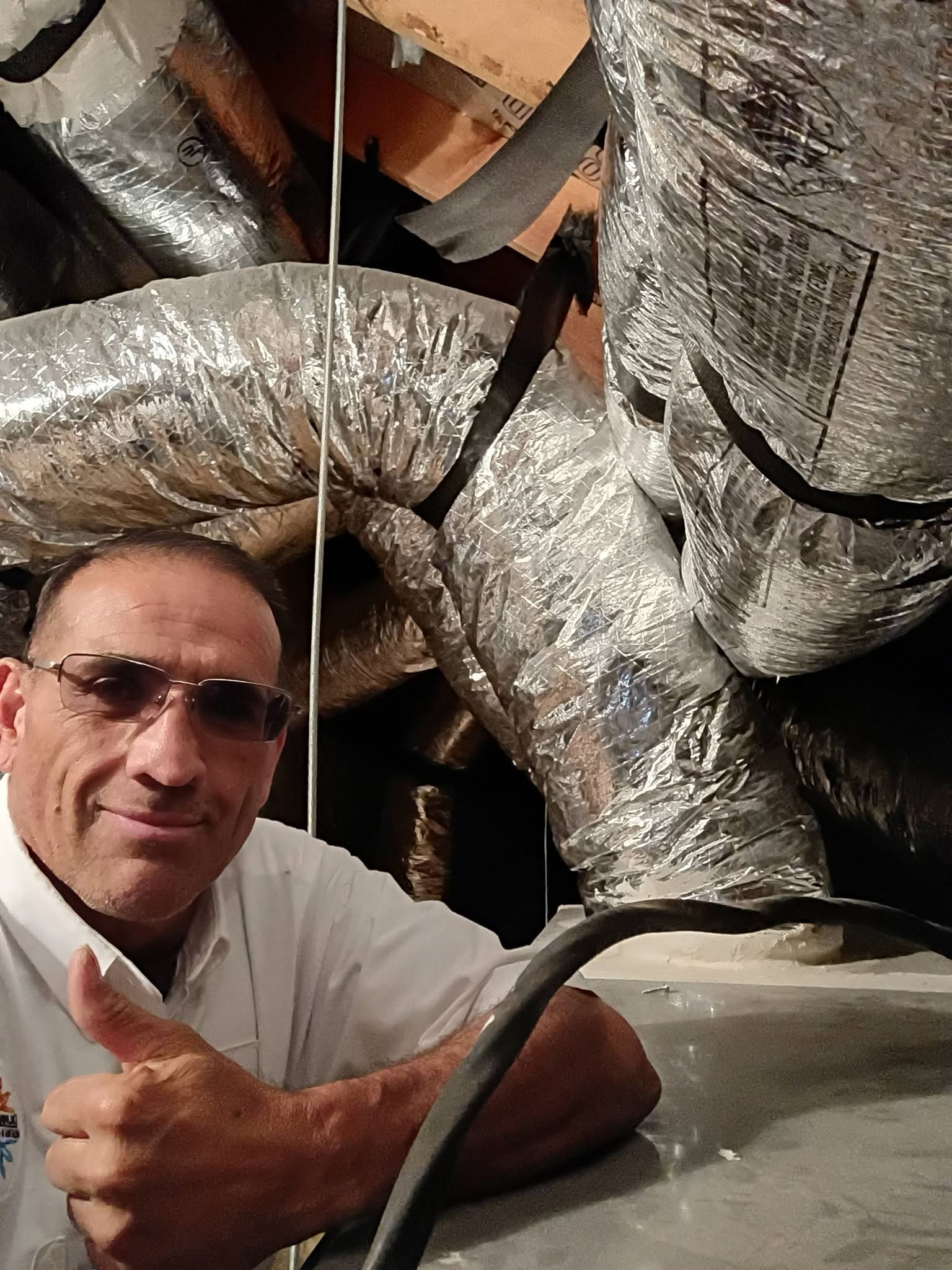 Manny giving a thumbs up next to attic ductwork