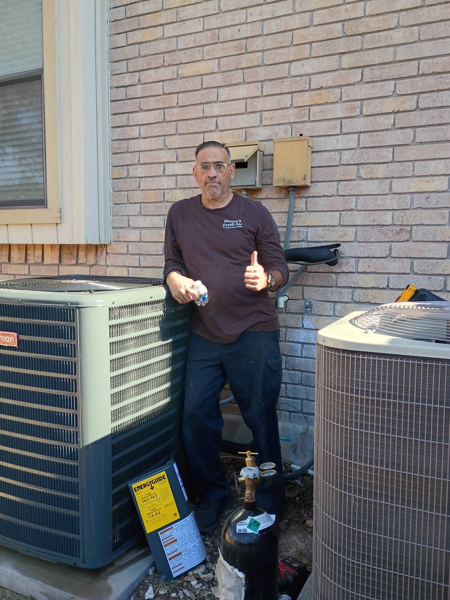 Manny giving a thumbs up next to a newly installed outdoor unit